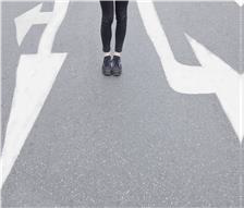 Symbolbild Person die auf der Straße zwischen Richtungsmarierungen steht.
