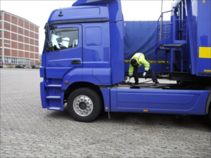 Ein Berufskraftfahrer schließt die Leitungen eines Sattelaufliegers an der Zugmaschine an