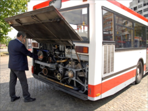 Ein Berufskraftfahrer prüft den Ölstand im Motorraum eines Bus