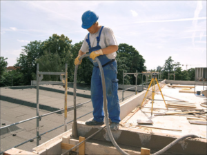 Ein Maurer füllt mit eiem Schlauch flüssigen Beton in eine Verschalung.